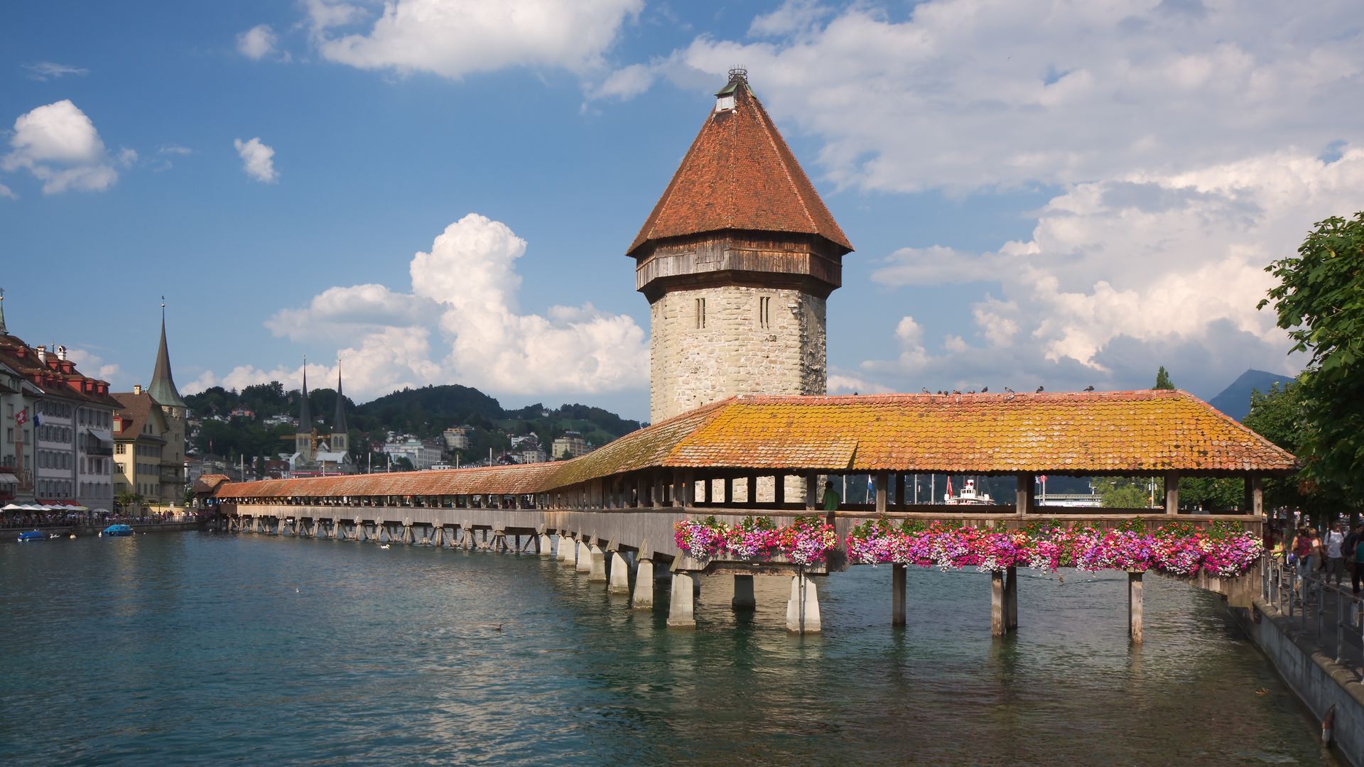 The Chapel Bridge and Water Tower over the river Reuss in Lucerne, with the Alps behind